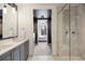 Bright bathroom features a double vanity and tiled shower with a glass door, and a view of the bedroom at 1750 Wewatta St # 1304, Denver, CO 80202