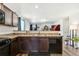 Open kitchen view featuring brown cabinetry, modern appliances, and eat-in bar with open view to living area at 47385 Lily Ave, Bennett, CO 80102