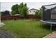 Spacious backyard featuring lush green grass, a wooden fence, a trampoline, and garden space at 10534 Ursula St, Commerce City, CO 80022