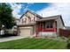 Inviting two-story home featuring a two-car garage, manicured lawn, and a covered front porch at 10534 Ursula St, Commerce City, CO 80022