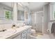 Bathroom featuring dual sinks, framed mirrors, a shower with glass door, and a view of green trees at 4338 S Alton St, Greenwood Village, CO 80111