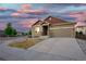 Inviting home featuring a well-kept lawn, stone accents, and a two-car garage under a striking sunset sky at 17857 Lapis Ct, Monument, CO 80132