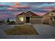 Inviting home featuring a well-kept lawn, stone accents, and a two-car garage under a striking sunset sky at 17857 Lapis Ct, Monument, CO 80132