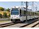 A white train on tracks with power lines overhead, showcasing public transportation options in the area at 3728 W 1St Ave, Denver, CO 80219