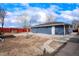 Backyard with a long patio, red fencing, and freshly painted blue exterior under an expanse of cloudy blue sky at 9101 Clarkson St, Thornton, CO 80229