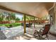 Spacious covered patio with outdoor dining and seating, overlooking a manicured lawn and garden at 2250 N Monaco Pkwy, Denver, CO 80207