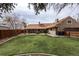 Large landscaped backyard featuring green grass, mature trees, and a covered patio at 2250 N Monaco Pkwy, Denver, CO 80207