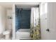 Clean bathroom features a tub with blue tile surround, patterned shower curtain, and a white cabinet at 2250 N Monaco Pkwy, Denver, CO 80207