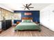 Well-lit bedroom features a wood-framed bed, wood flooring, a ceiling fan, and a striking blue accent wall at 2250 N Monaco Pkwy, Denver, CO 80207