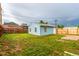 Backyard view featuring a grassy lawn, wooden fence, and light blue detached house at 5001 W Nevada Pl, Denver, CO 80219
