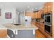 Spacious kitchen featuring wood cabinets, stainless steel appliances, and a large granite island with a sink at 12942 Leyden St, Thornton, CO 80602