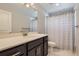 Bright bathroom featuring a modern vanity, sink, and shower with a neutral-toned shower curtain at 7933 Florado St, Denver, CO 80221