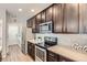 Updated kitchen with stainless steel appliances, granite countertops and sleek dark wood cabinetry and backsplash at 7933 Florado St, Denver, CO 80221