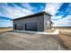 A spacious two-car garage with modern doors and ample parking space on a gravel driveway at 65960 E Evans Pl, Byers, CO 80103