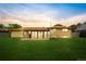 Beautiful backyard with a large green lawn, mature trees, and a sunroom bathed in evening light at 85 S Flower St, Lakewood, CO 80226