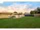 Spacious backyard at sunset featuring a lush lawn, mature trees, sunroom, and a storage shed at 85 S Flower St, Lakewood, CO 80226