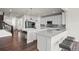 Bright open concept kitchen boasts white cabinets, a large island with seating, and hardwood floors at 7166 S Vandriver Way, Aurora, CO 80016