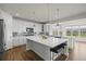 Spacious kitchen featuring white cabinets, gray backsplash, a large island, stainless steel appliances, and hardwood floors at 7166 S Vandriver Way, Aurora, CO 80016
