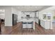Bright kitchen boasts white cabinets, a large island with seating, and stainless steel appliances at 7166 S Vandriver Way, Aurora, CO 80016
