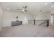 Open loft area with neutral walls, carpet flooring, a ceiling fan, and staircase with decorative railing at 7166 S Vandriver Way, Aurora, CO 80016