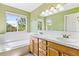 Well-lit bathroom featuring dual sinks, a large mirror, and a separate soaking tub at 2330 S Salem Cir, Aurora, CO 80014
