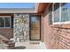 Close-up of the front door featuring a stone accent wall, brick siding, and modern lighting at 4080 E Caley Cir, Centennial, CO 80121