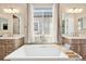 This bathroom showcases dual vanities, a soaking tub centered by a window, and stylish fixtures, offering an elegant retreat at 6980 S Yantley Ct, Aurora, CO 80016
