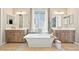 This bathroom has dual vanities, a soaking tub centered by a window, and stylish fixtures, offering an elegant retreat at 6980 S Yantley Ct, Aurora, CO 80016