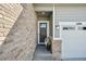Inviting front entry with a modern front door, brick accents, and an attached two-car garage at 6980 S Yantley Ct, Aurora, CO 80016