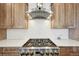 Gourmet stainless steel stove top with hood and custom cabinetry are featured at 6980 S Yantley Ct, Aurora, CO 80016
