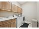 Bright laundry room featuring modern appliances, wooden cabinets, and a utility sink at 6980 S Yantley Ct, Aurora, CO 80016