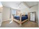 Bright and airy main bedroom featuring a large bed with blue bedding, a window, and a full-length mirror at 6980 S Yantley Ct, Aurora, CO 80016