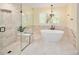 Bright bathroom featuring a glass shower and soaking tub with a modern light fixture at 930 W Dry Creek Rd, Littleton, CO 80120