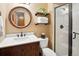 Bathroom features wood vanity with a round mirror, shower, and decorative wall shelving at 930 W Dry Creek Rd, Littleton, CO 80120