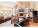 Inviting living room with a brick fireplace, comfortable leather seating, and ample natural light from large windows at 930 W Dry Creek Rd, Littleton, CO 80120