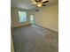Bright living room with large window, sliding glass door to patio, neutral carpeting, and ceiling fan at 17346 Nature Walk Trail Trl # 105, Parker, CO 80134