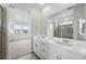 Bright bathroom featuring dual sinks, large mirror, and glass-enclosed shower with neutral tiles at 39732 Penn Rd, Elizabeth, CO 80107