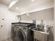 Functional laundry room with a modern washer and dryer, stainless steel sink, and storage shelf at 5700 E Bayaud Ave, Denver, CO 80224