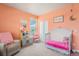 Charming bedroom with peach walls, crib, play kitchen, and view of the outside at 4532 Dewey Ln, Brighton, CO 80603