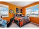 Bright bedroom featuring orange walls, a Chicago Bears theme, and two windows at 4532 Dewey Ln, Brighton, CO 80603