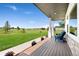 Inviting covered porch with wood flooring and seating overlooks a spacious, lush front yard at 3047 Deer Creek Ranch Loop, Parker, CO 80138