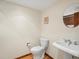 Small half bathroom with a pedestal sink, toilet, and round mirror on the wall at 1276 Harrison Ct, Boulder, CO 80303