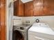 Laundry room with stainless steel washer, white dryer, and wooden cabinets at 1276 Harrison Ct, Boulder, CO 80303