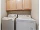 Functional laundry area featuring a stacked washer and dryer setup with overhead storage cabinets at 4733 Flower St, Wheat Ridge, CO 80033