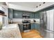 Modern kitchen featuring updated appliances, granite countertops, and stylish sage cabinets with light-colored walls and natural lighting at 6662 Fonder Dr, Parker, CO 80134