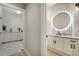 Modern bathroom showcasing a round, backlit mirror above a vanity with sleek, dark hardware at 24031 E Hinsdale Pl, Aurora, CO 80016