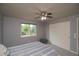 Cozy bedroom with a ceiling fan, neutral walls, carpet, and a view of the backyard trees through a window at 14962 Williams St, Thornton, CO 80602