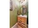 Powder room with wooden vanity, gold accents, decorative mirror, and green wall at 4918 Preserve Pl, Firestone, CO 80504