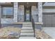 Inviting front entrance featuring a green door, stone pillars, black iron railing, and freshly landscaped yard at 5575 Moosehead Cir, Longmont, CO 80503