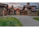 Stunning mountain home featuring a stone and wood exterior, porte-cochere, and circular driveway at sunset at 220 Cottonwood Cir, Breckenridge, CO 80424